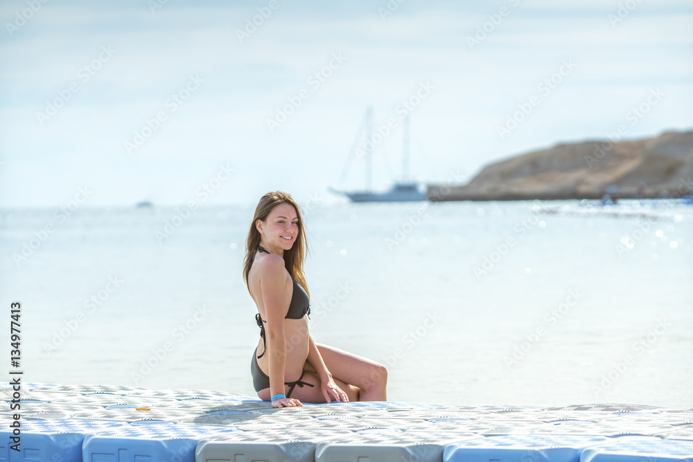 The young woman sit against the background of the sea
