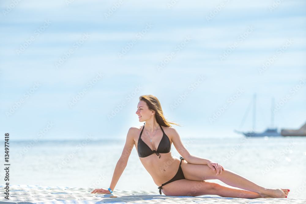 The beautiful woman sit against the background of the sea The beautiful woman sit against the background of the sea