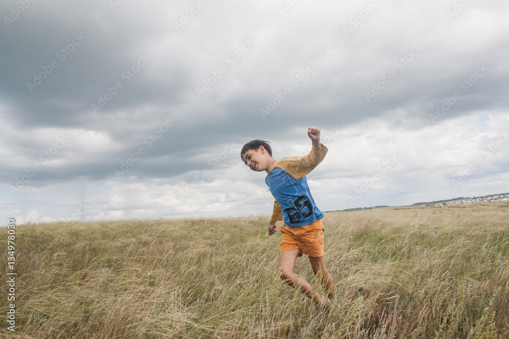 Boy shows a plane. boy running in a field. boy in shorts. boy stands in the desert. feather in the field. boy looking up at the sky. dreamer Boy shows a plane. boy running in a field. boy in shorts. boy stands in the desert. feather in the field. boy looking up at the sky. dreamer
