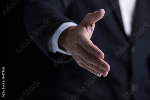 A business man wearing black suit giving one hand for shaking in cooperate look.