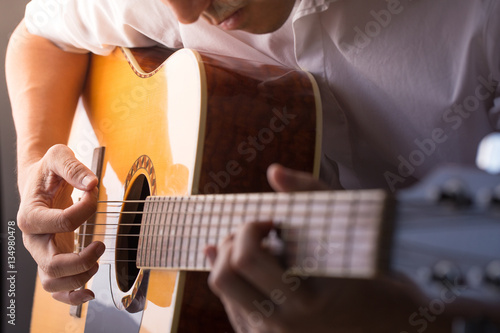 A man sitting and playing classic wooden guitar close up to chord tab fretboard. photo