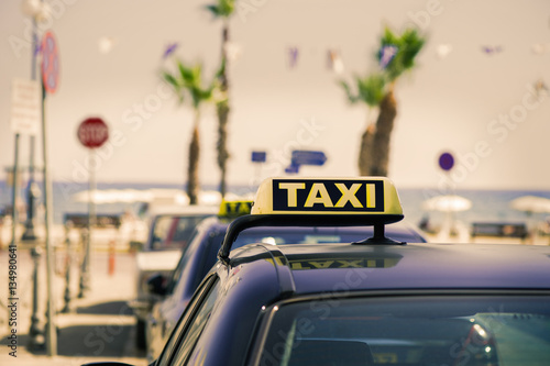 Taxi car on the street of Larnaca. Cyprus. Luminous taxi sign on beach background.