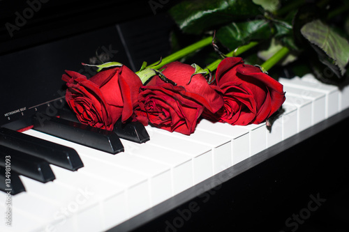 Красные розы лежат на пианино 