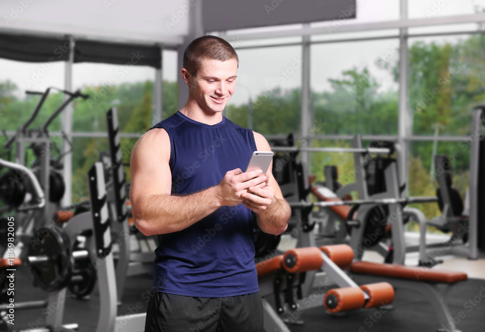 Young handsome man with cellphone in gym Young handsome man with cellphone in gym