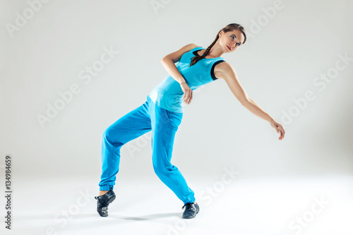 Young beautiful slim girl in blue dancing on a white studio background