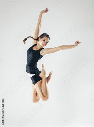 Young beautiful slim girl with hair braid doing dance or pilates exercise on white studio background