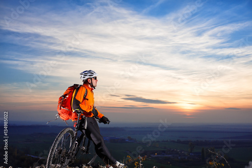 Cyclist with backpack on the top of a hill