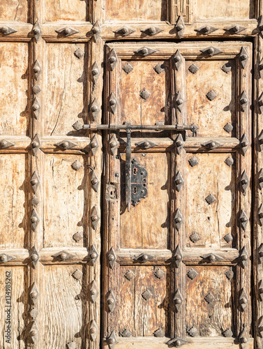 ancient brown wooden door with metallic ornaments and a big bolt