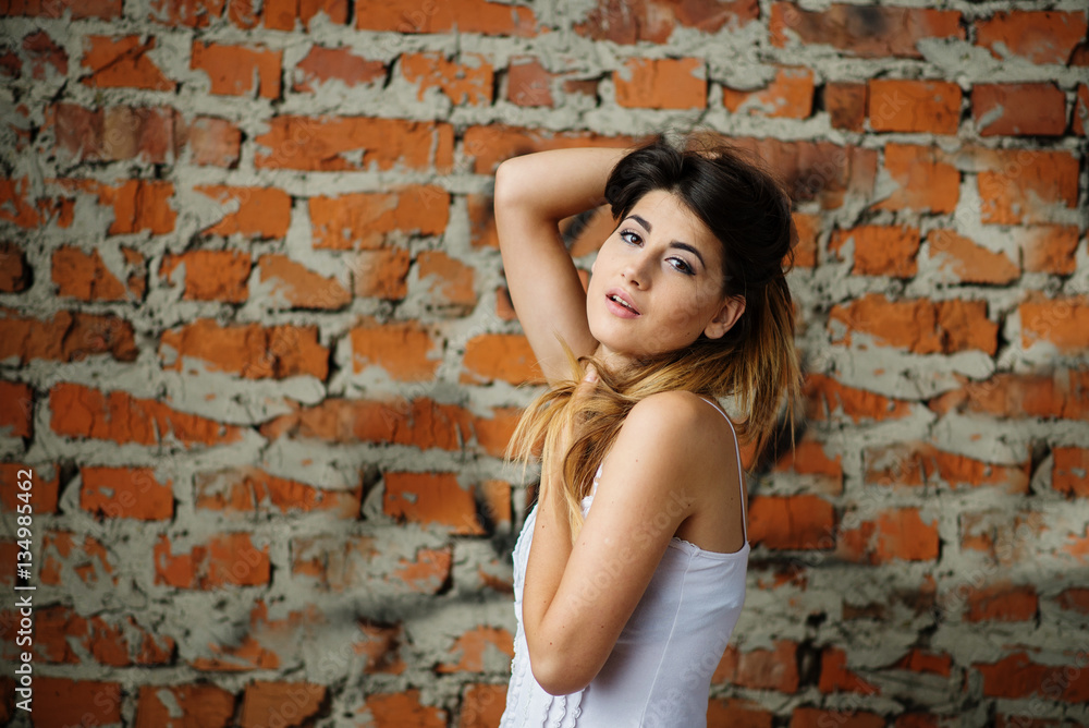 Portrait of young cute brunette girl background brick wall.