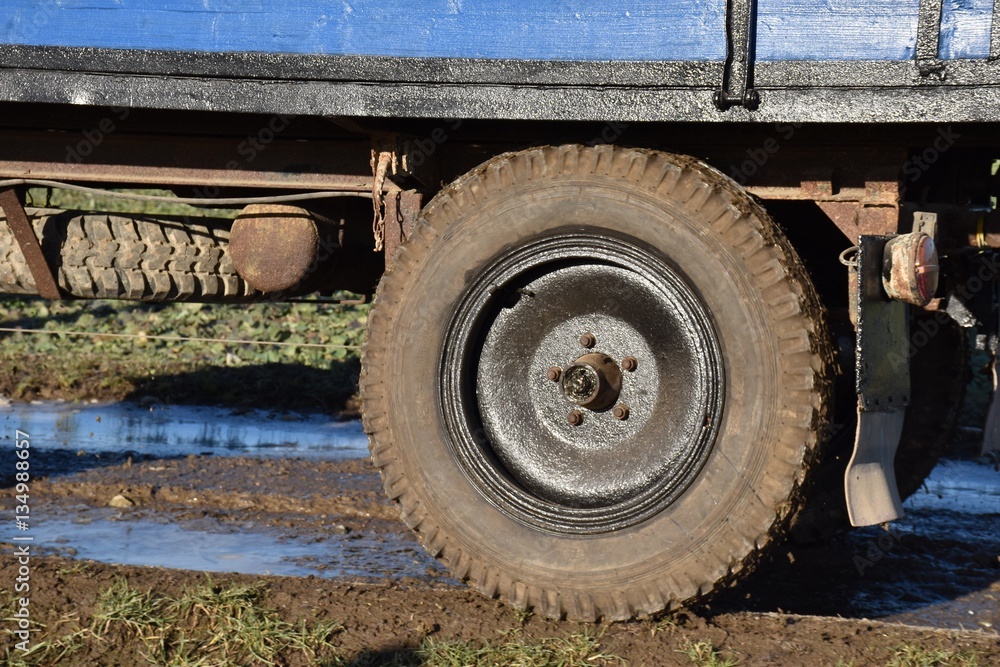 Tyre of a tractor trailer. Agriculture in action. Field with blue puddles.
