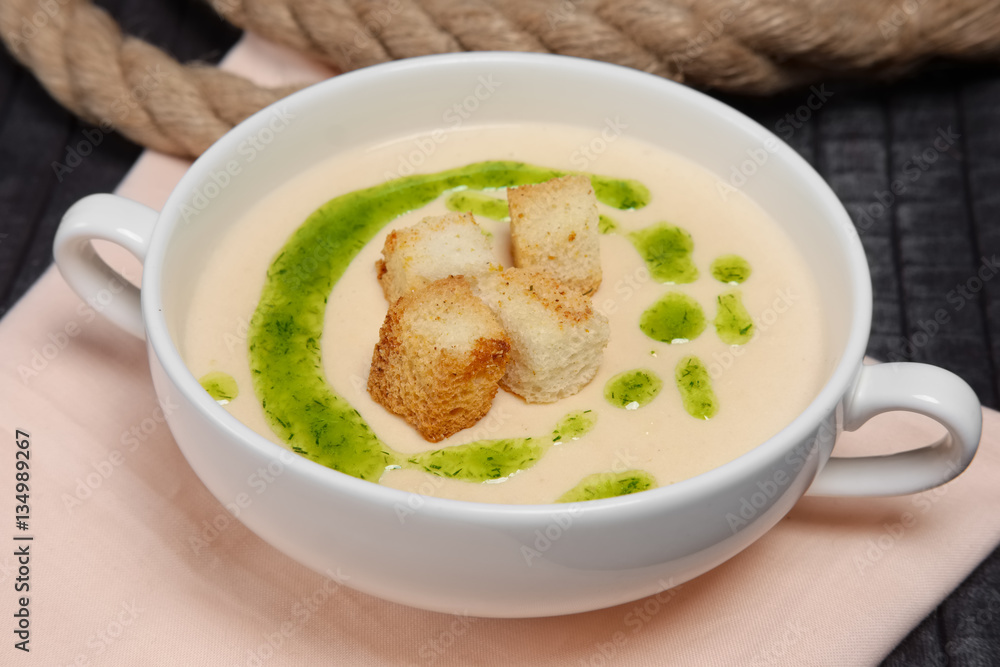 Creamy soup puree in white bowl and small pieces of fried bread Creamy soup puree in white bowl and small pieces of fried bread