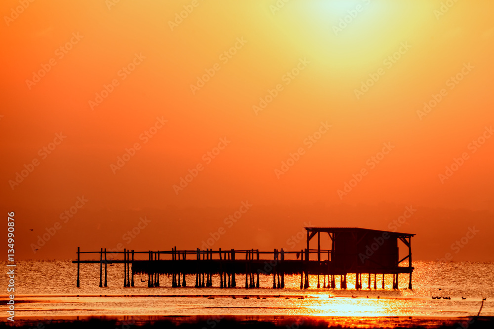 Long exposure of magic sunrise over the ocean with a hut in the