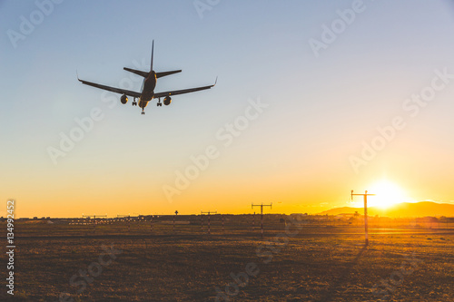 Airplane landing at sunset, bottom view