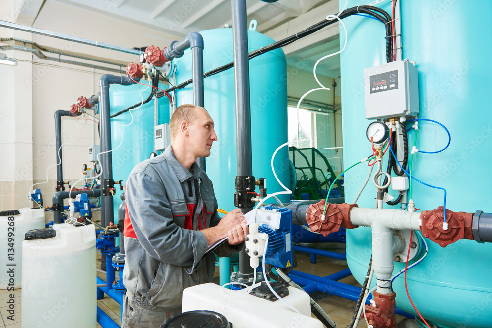 Obraz premium serviceman operating industrial water purification or filtration equipment