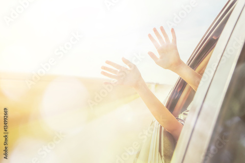 Person's hands out of the car window driving down a country road