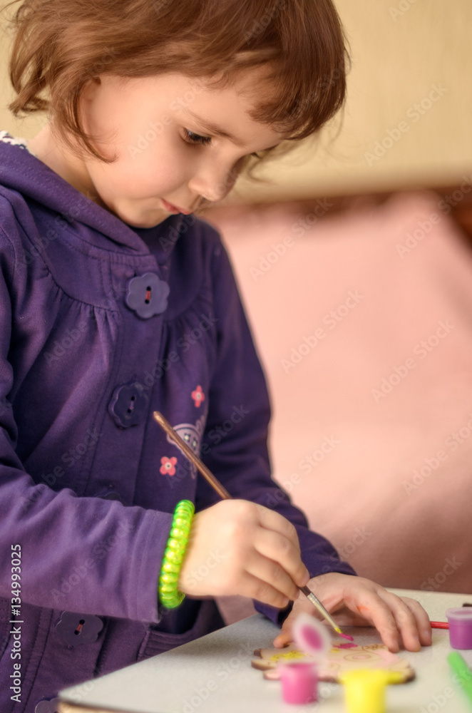 Little girl painting toy with paintbrush at home Little girl painting toy with paintbrush at home