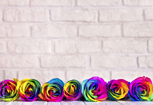 Rainbow roses on white bricks and wood background. Postcard for Valentine's and Mother's day