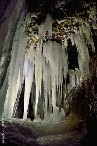 Winter icicles iluminated with battery and candles. Frozen cave in Slovakia. Stalactite and stalagmite. Exploration depths of the earth. © matkovci