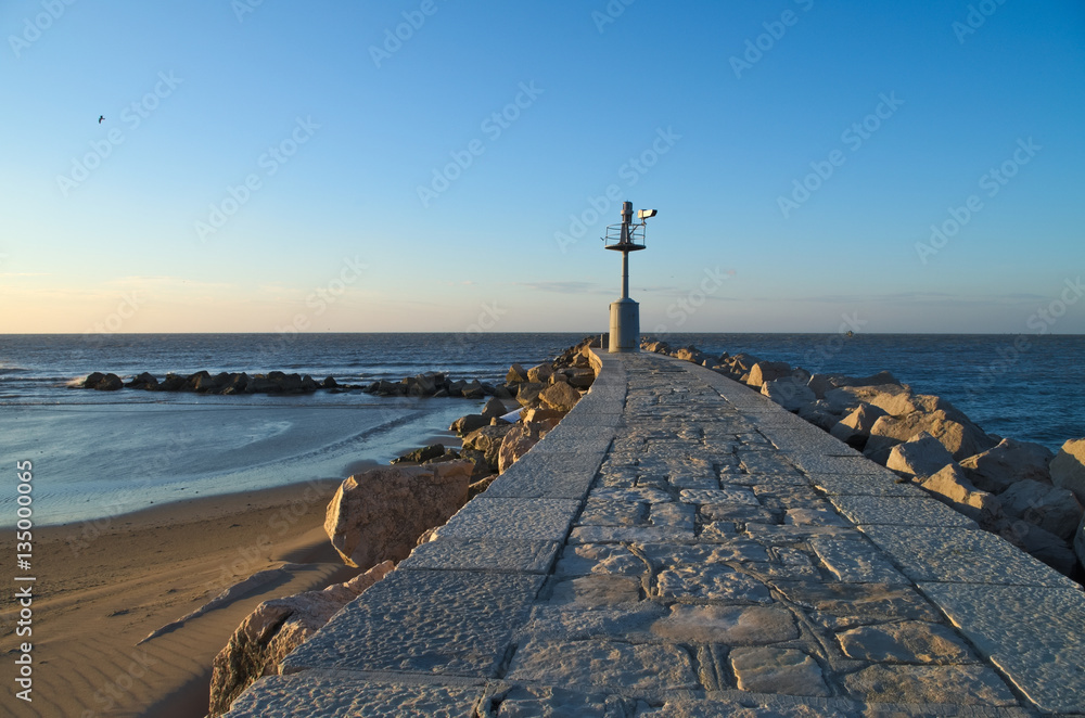 Sunrise on the old lighthouse on the breakwater of the village of Grado, Italy
