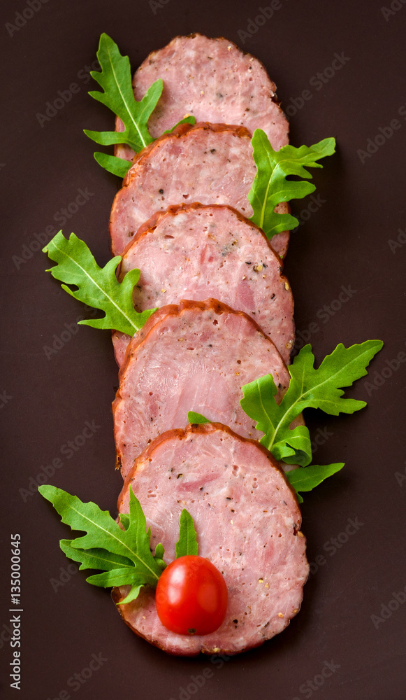 Smoked sausage with arugula lettuce and tomatoes on a dark brown background Smoked sausage with arugula lettuce and tomatoes on a dark brown background