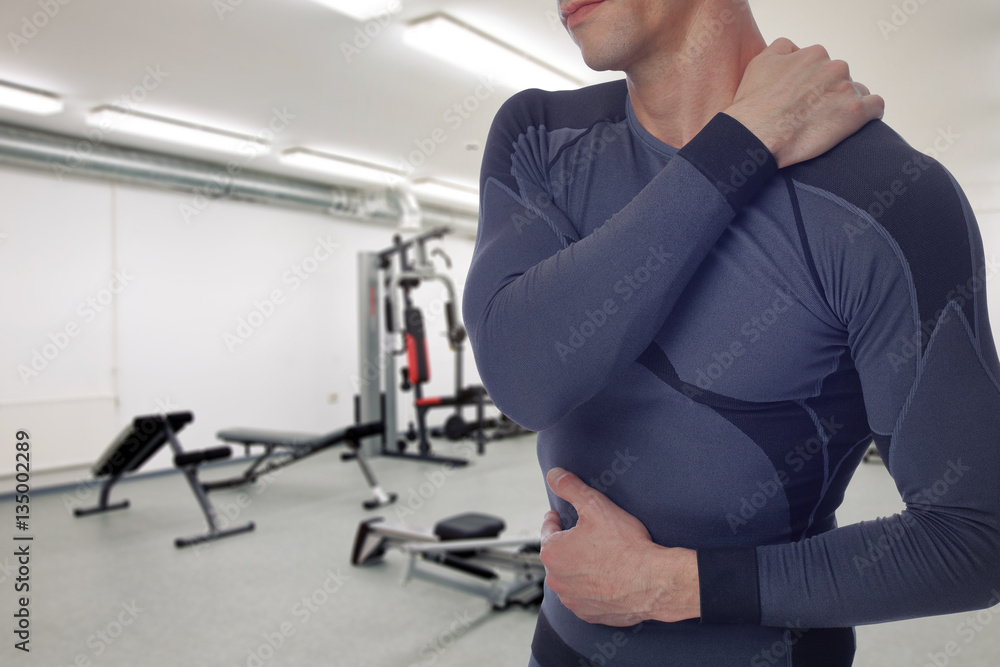 Man with back and neck pain in gym. Sports exercising injury.