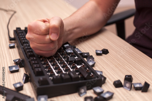 Man smashes a mechanical computer keyboard in rage using one fist photo