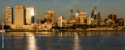 OCT 15, 2016, Philadelphia, PA skyscrappers and skyline at sunrise reflect golden light in Delaware River, as seen from Camden, NJ