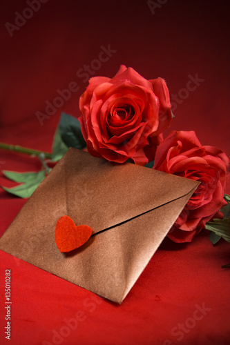 Fototapeta Naklejka Na Ścianę i Meble -  Valentine's Day: Golden copper envelope with a letter and red roses on red background