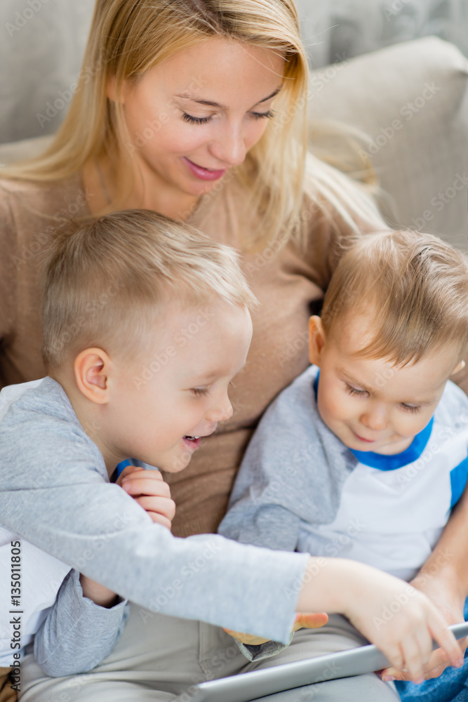 Loving family using a digital tablet together, mother with her sons at home Loving family using a digital tablet together, mother with her sons at home