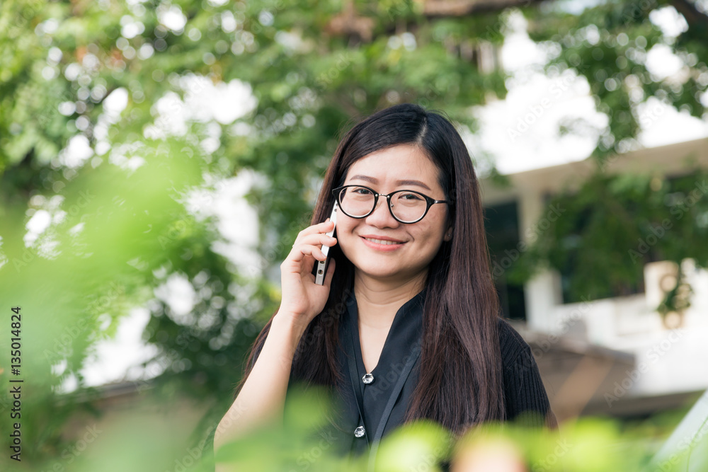 Asian glasses business women talking cellphone in park Asian glasses business women talking cellphone in park