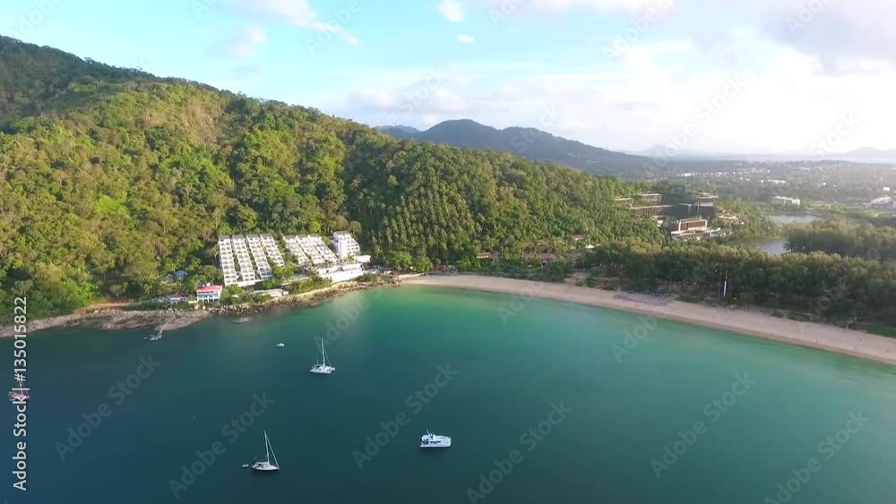 Aerial: Nai Harn beach in sunrise time look around. HD birds eye view. Blue water with rocks, jungle on background. Aerial: Nai Harn beach in sunrise time look around. HD birds eye view. Blue water with rocks, jungle on background.