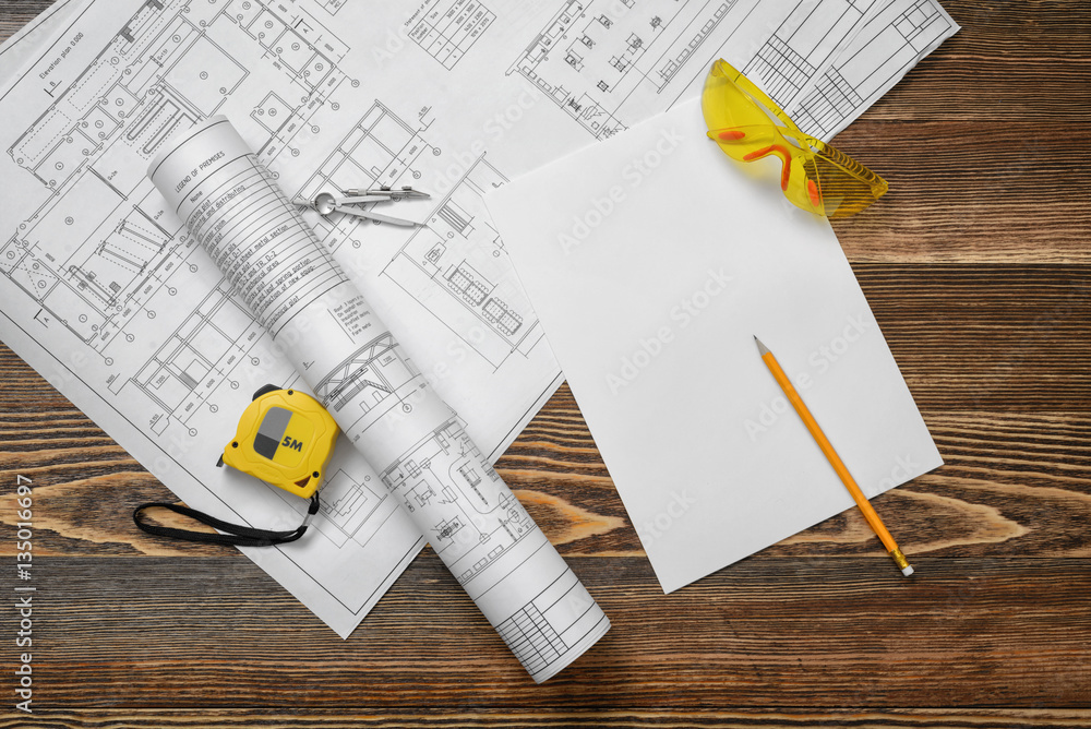Φωτογραφία Blueprints on wooden background with piece of paper, compass, pencil, measuring tape and protective glasses