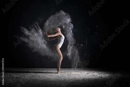 Slender blonde dancing in white dust studio shot
