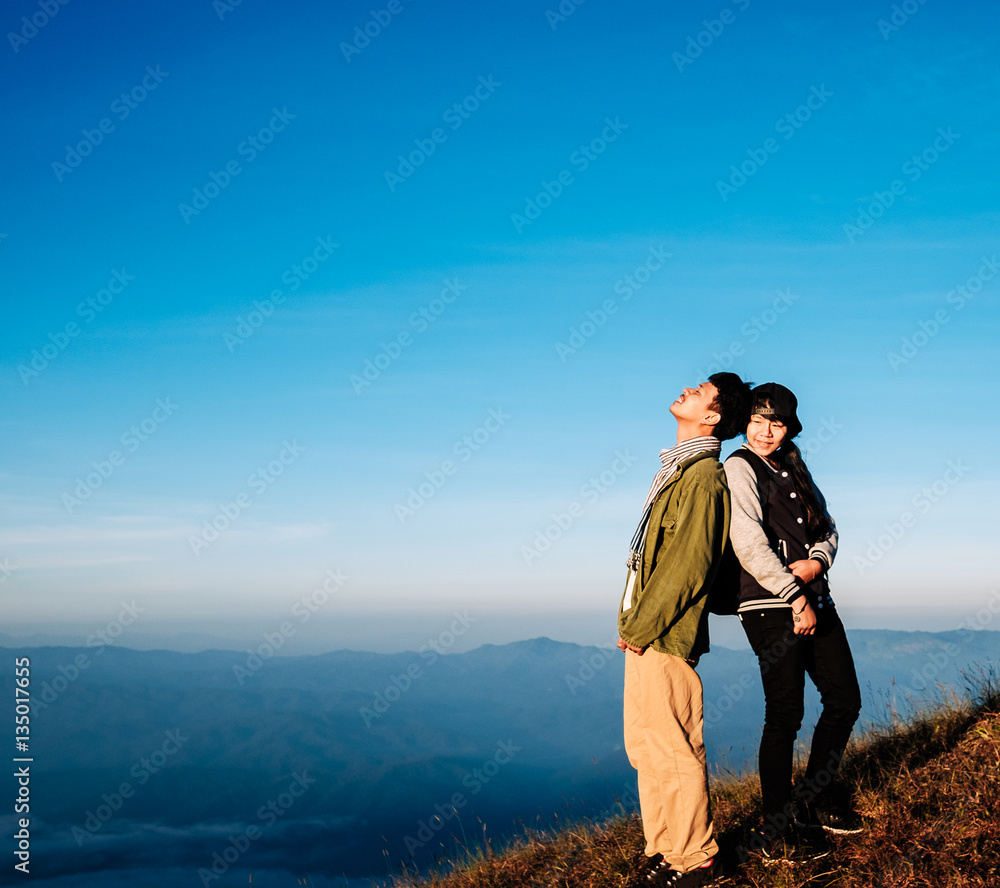 young adult asian couple standing together enjoys rise to the top of the mountain with light of morning in vintage style