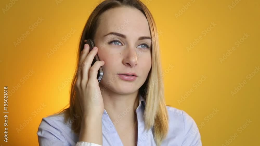Beautiful young woman talking on mobile phone on yellow background. Beautiful young woman talking on mobile phone on yellow background.