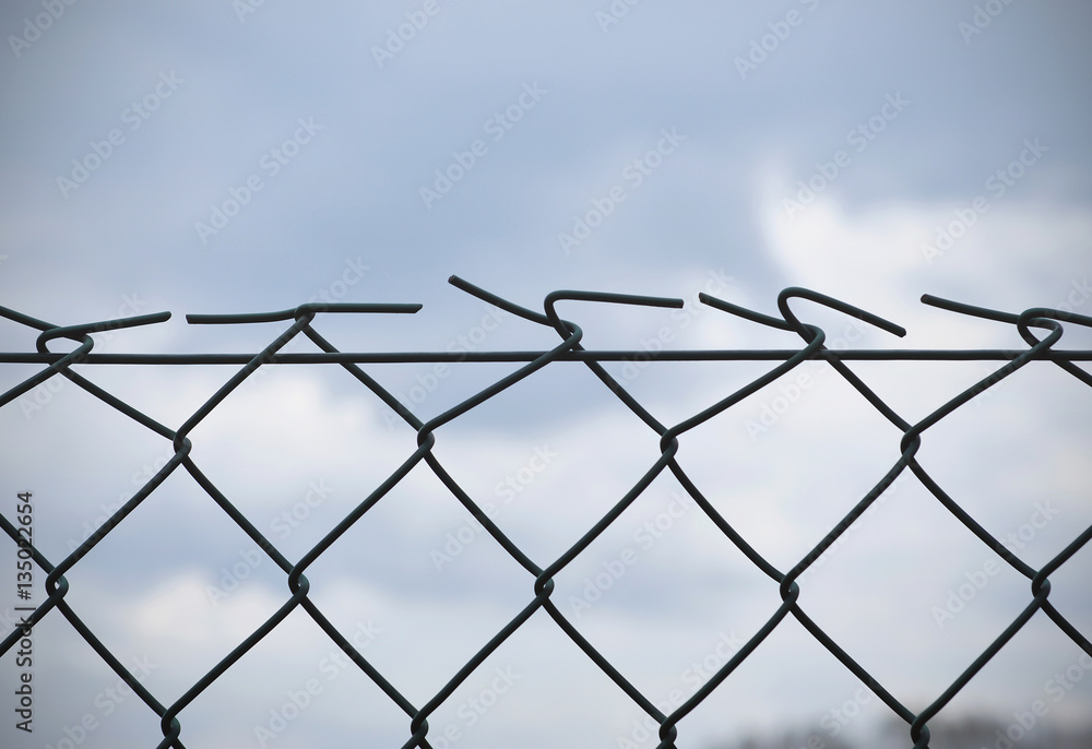 Barbed wire, fence in front of gray sky, background Barbed wire, fence in front of gray sky, background
