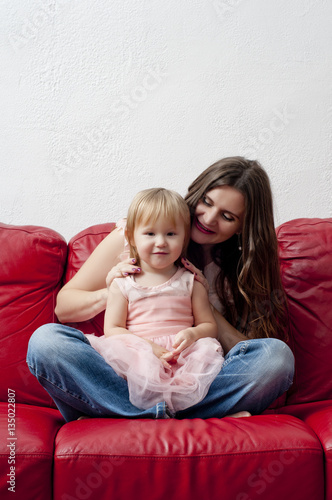Beautiful girl playing with her daughter sitting on the couch