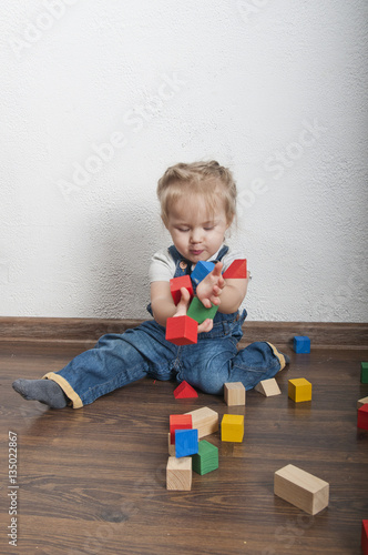 Little cute girl playing with a wooden constructor