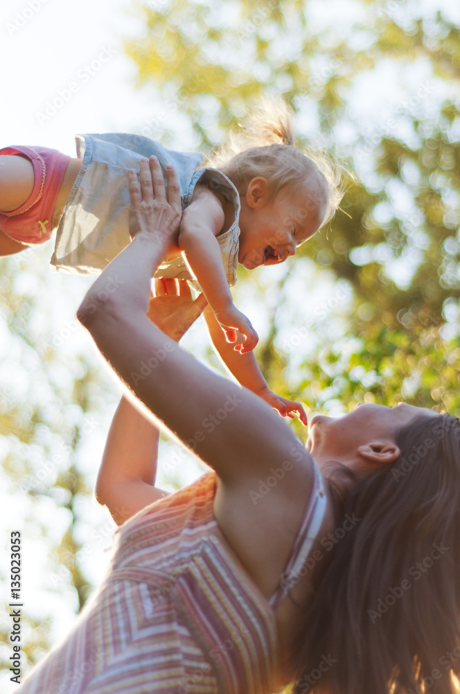 Naklejka premium Young mother throws his little daughter in the air