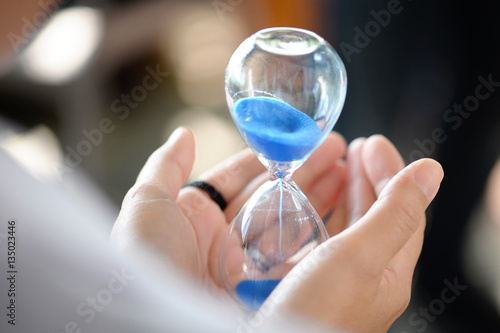 Hourglass that is located on the beautiful hands.