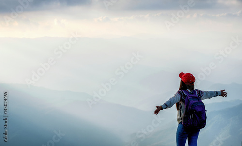 young adult girl with arms spread wide enjoys rise to the top of mountain