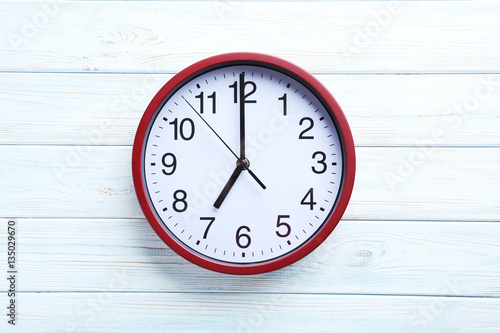 Red round clock on a white wooden table