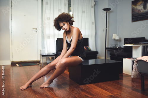Black topless woman with afro hairstyle sitting in a couch
