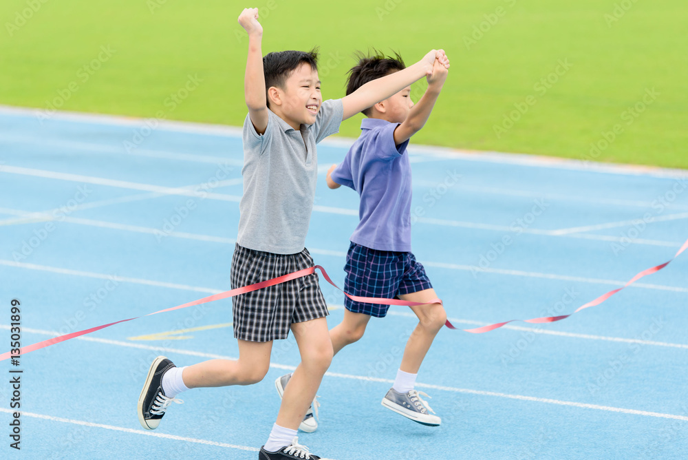 Fototapeta premium Young Asian boy running on blue track in the stadium