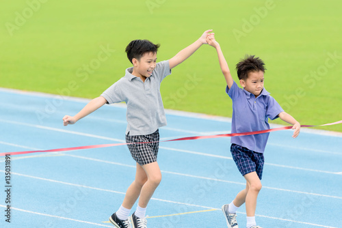 Young Asian boy running on blue track in the stadium © TinPong