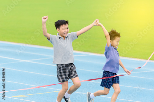 Young Asian boy running on blue track in the stadium