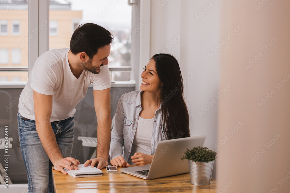 Couple working together at home, looking at each other and smili Couple working together at home, looking at each other and smili