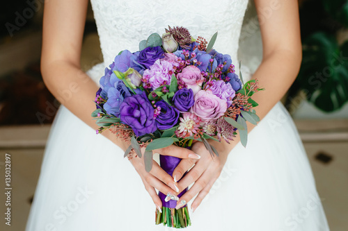 the bride holding a purple bouquet. wedding flowers. soft focus.