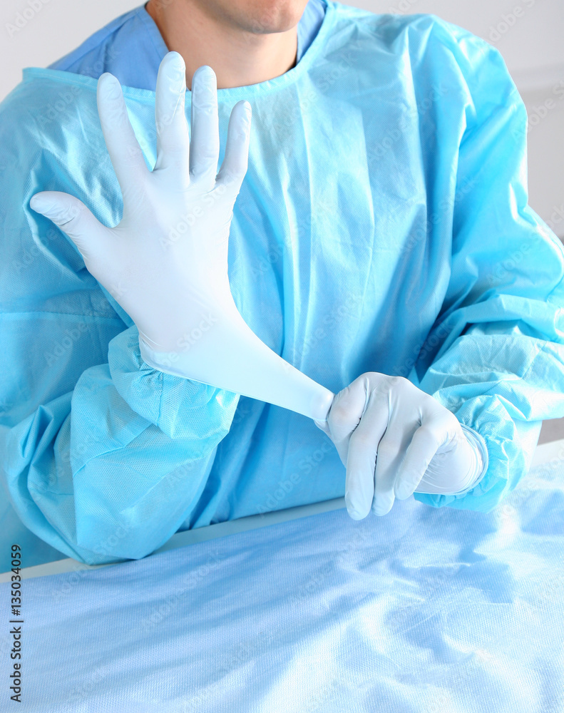 Doctor putting on sterile gloves isolated white Doctor putting on sterile gloves isolated white