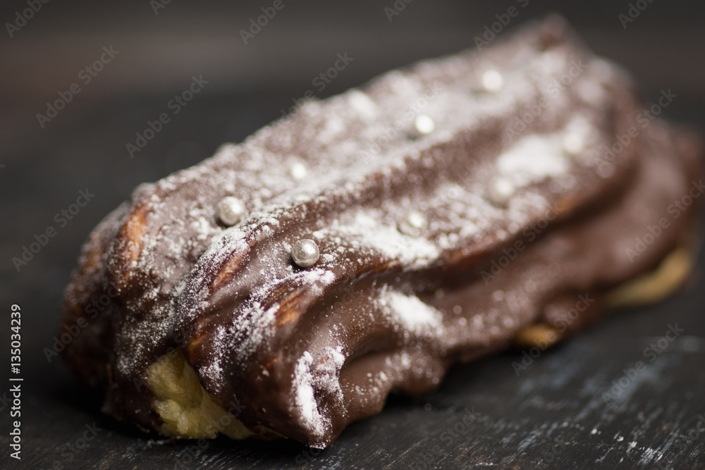 Chocolate eclair on the dark background. Shallow depth of field. Chocolate eclair on the dark background. Shallow depth of field.